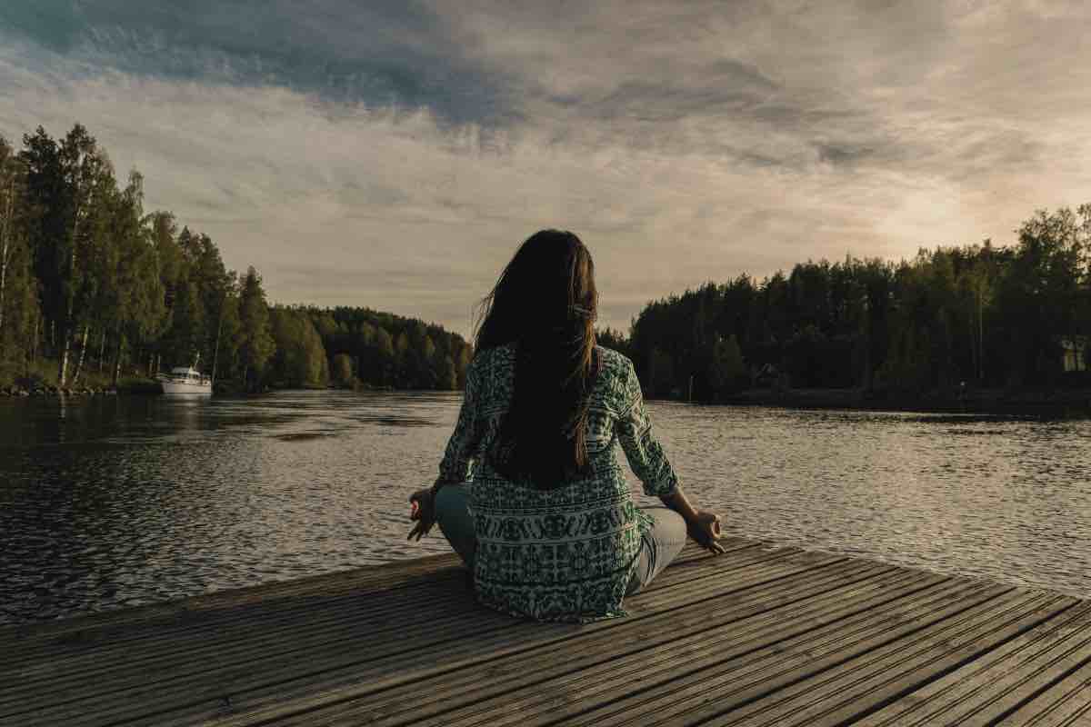 Donna medita sulla riva di un lago all'imbrunire